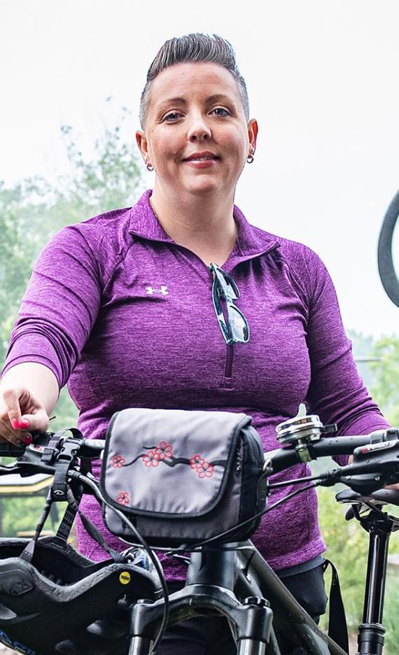 Teri Luce is standing in front of the mastodon statue with her bike.